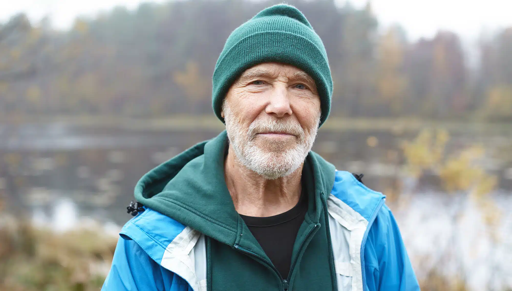 Portr&auml;t des 62-j&auml;hrigen Guido in Outdoor-Kleidung vor einer Naturkulisse. Als ehemaliger starker Raucher teilt er in seinem Erfahrungsbericht, wie er mit Asmoken den Ausstieg geschafft hat.