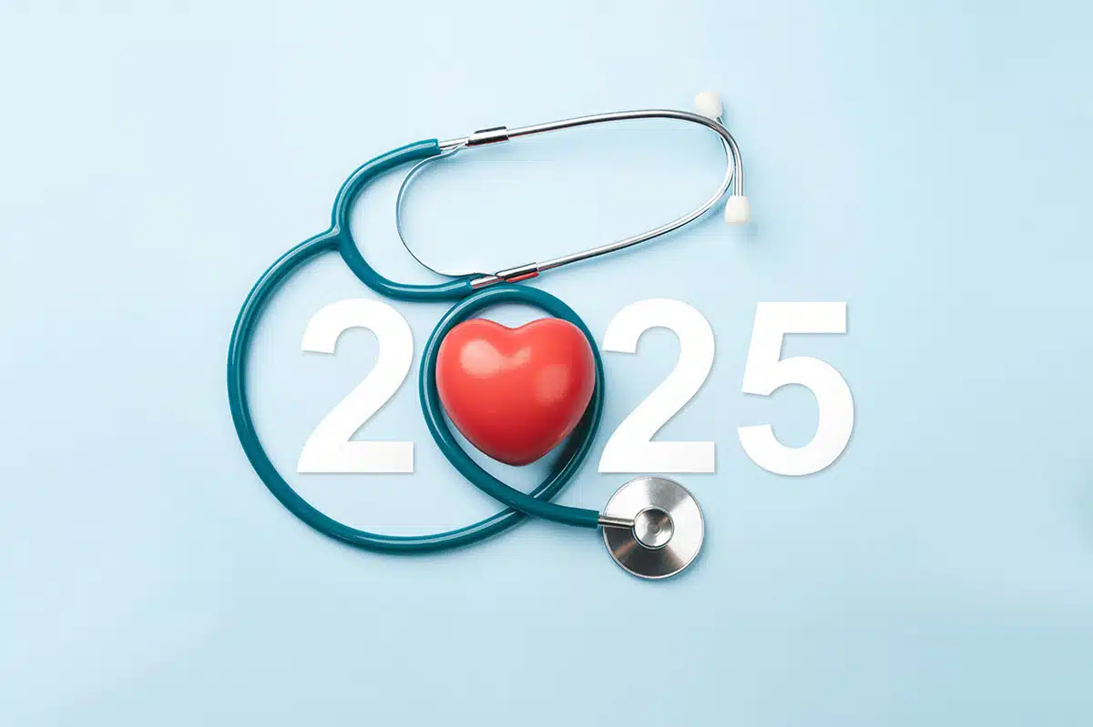 Ein Stethoskop und ein rotes Herz sind um die Jahreszahl ‚2025‘ angeordnet, alles auf einem hellblauen Hintergrund. Das Bild symbolisiert den Vorsatz für ein gesünderes Jahr und die Möglichkeit, mit Unterstützung von Asmoken einen Rauchstopp als wichtigen Gesundheitsschritt zu planen.