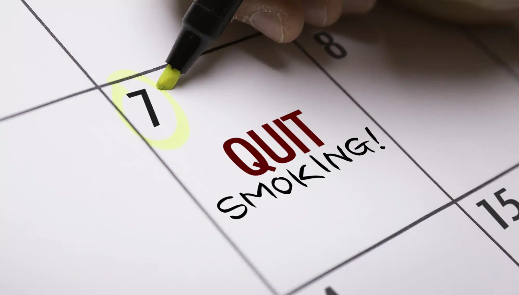Nahaufnahme einer Hand, die mit einem gelben Textmarker den 7. Tag in einem Kalender markiert. Im Kalenderfeld steht in großen Buchstaben ‚QUIT SMOKING!‘. Das Bild symbolisiert den ersten Schritt der gezielten Planung und Vorbereitung auf ein rauchfreies Leben mit Unterstützung von Asmoken.