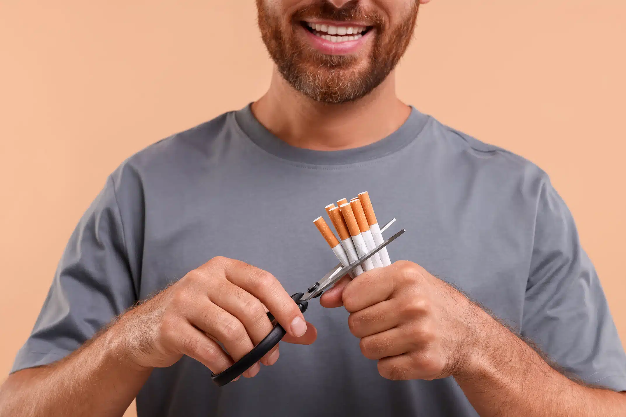 Ein lächelnder Mann mit Bart bereitet in einer hellen Küche frisches Gemüse wie Paprika, Tomaten und Karotten zu. Vor ihm steht eine Kamera auf einem Stativ, die den Kochvorgang aufzeichnet. Das Bild symbolisiert die Freude an einem gesunden, rauchfreien Lebensstil und die Wiederentdeckung von Genuss durch eine ausgewogene Ernährung nach dem Rauchstopp mit Asmoken.