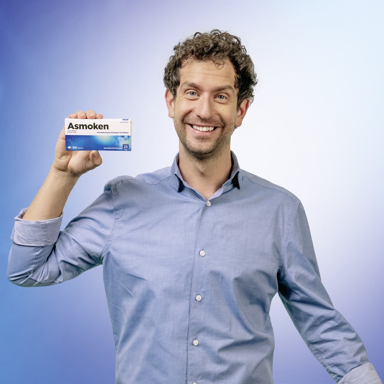 Quadratisches Porträt eines lächelnden Mannes, der eine Packung Asmoken präsentiert – Ein freundliches Motiv zur Unterstützung der Raucherentwöhnung.
