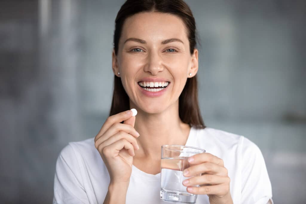 Frau mit Wasserglas und Tablette